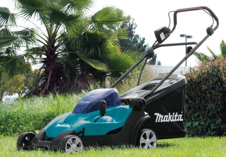 A Makita cordless battery-powered lawn mower standing on a mown lawn.