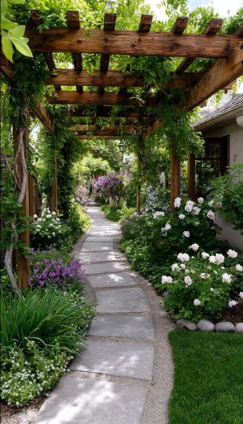 A timber pergola over a curving flagstone path, planted with roses and bellflowers.